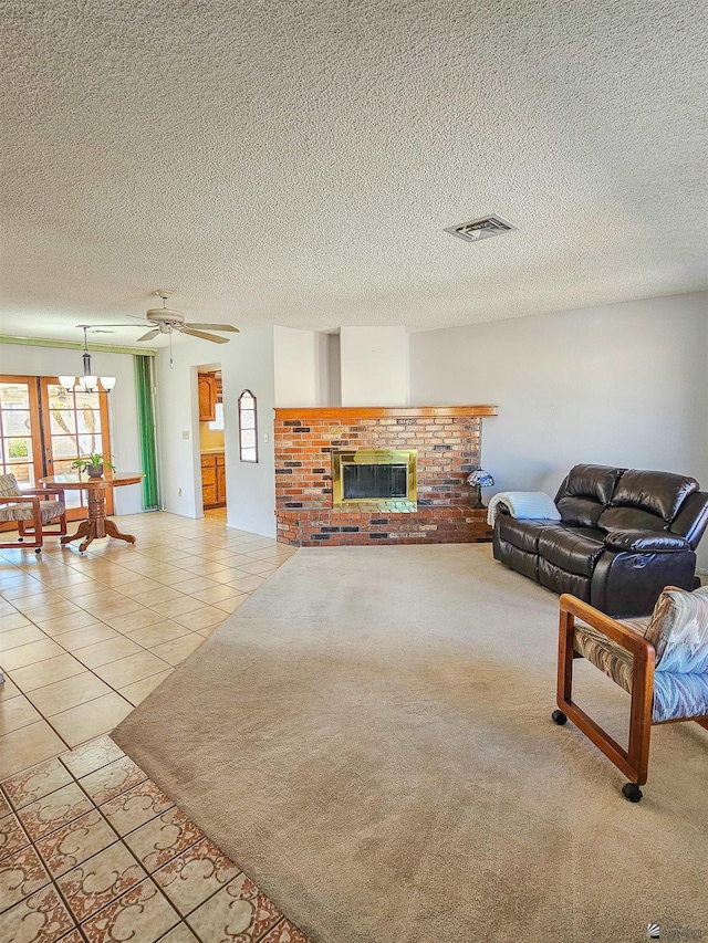 tiled living room with ceiling fan with notable chandelier, a brick fireplace, and a textured ceiling