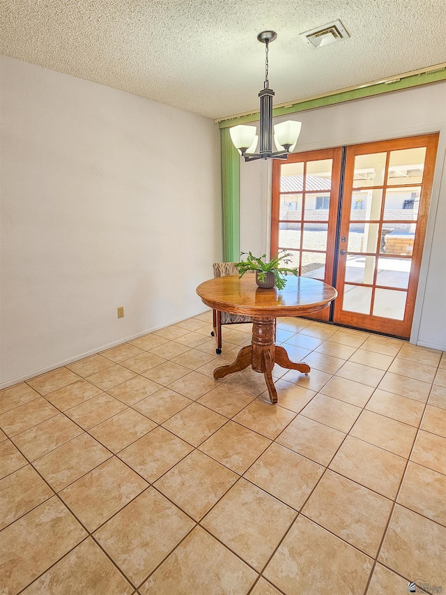 dining space with a textured ceiling, a notable chandelier, and light tile patterned floors