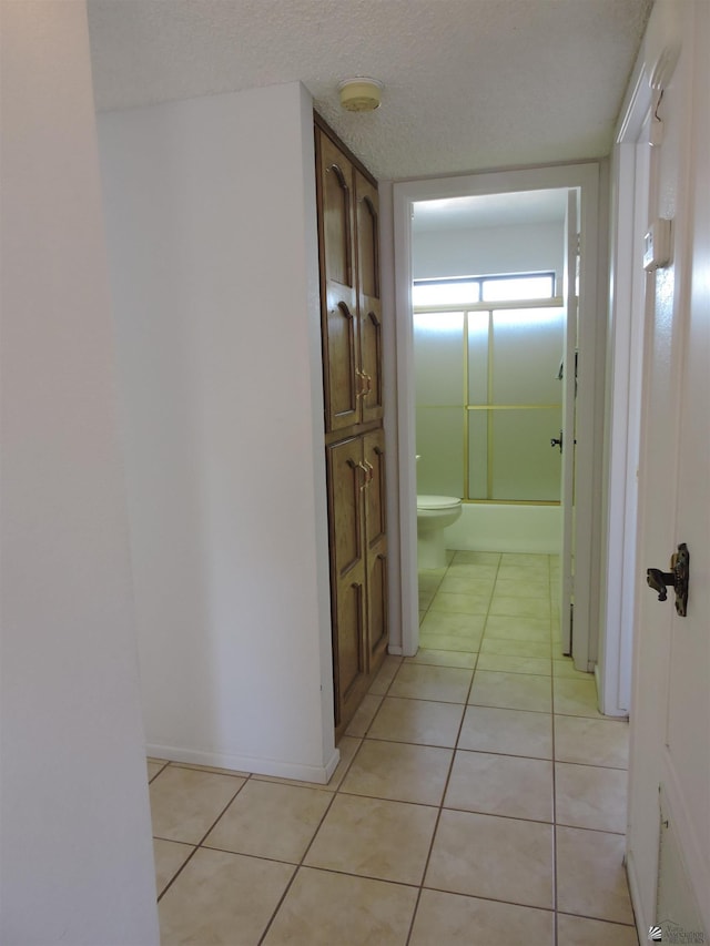 hall featuring a textured ceiling and light tile patterned flooring