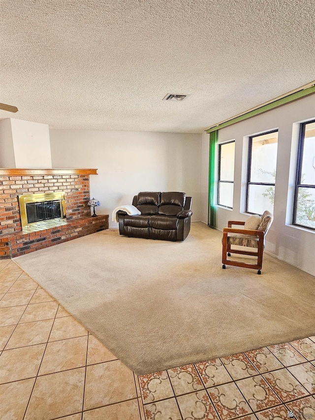 living room featuring a brick fireplace, a textured ceiling, and light tile patterned flooring