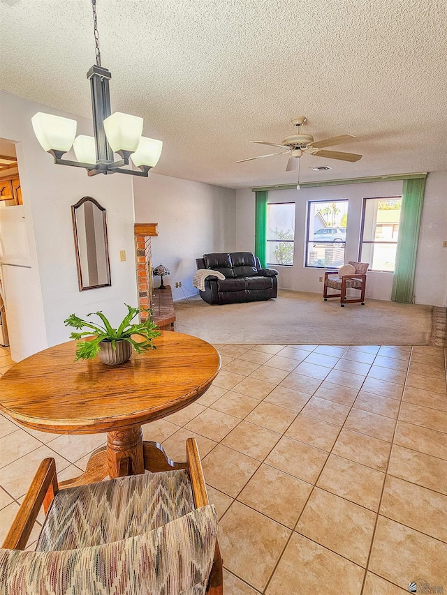 dining space with ceiling fan with notable chandelier, light tile patterned flooring, and a textured ceiling