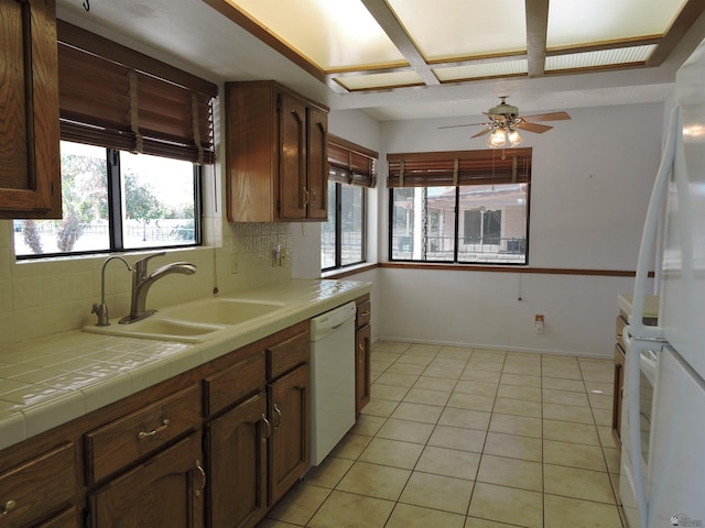 kitchen featuring white appliances, light tile patterned floors, tile countertops, sink, and backsplash