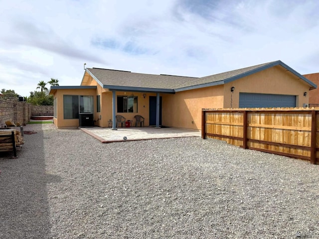 rear view of property with a patio area, fence, and stucco siding