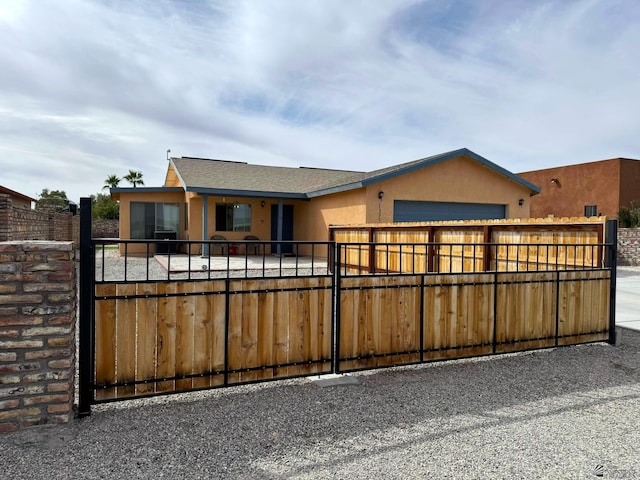 view of front of home featuring an attached garage, fence, driveway, a gate, and stucco siding