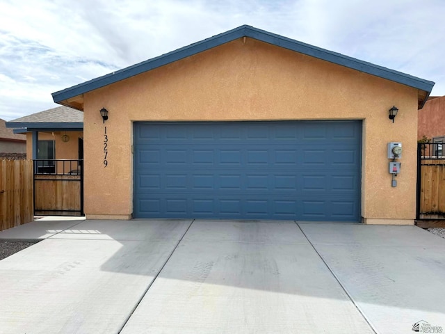 garage with concrete driveway and fence