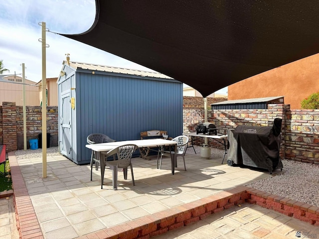 view of patio with an outbuilding, a storage shed, area for grilling, and fence