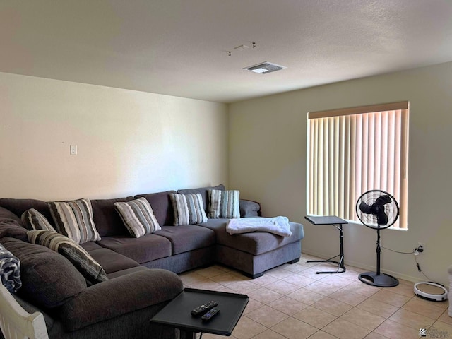 living room with light tile patterned floors, baseboards, visible vents, and a textured ceiling