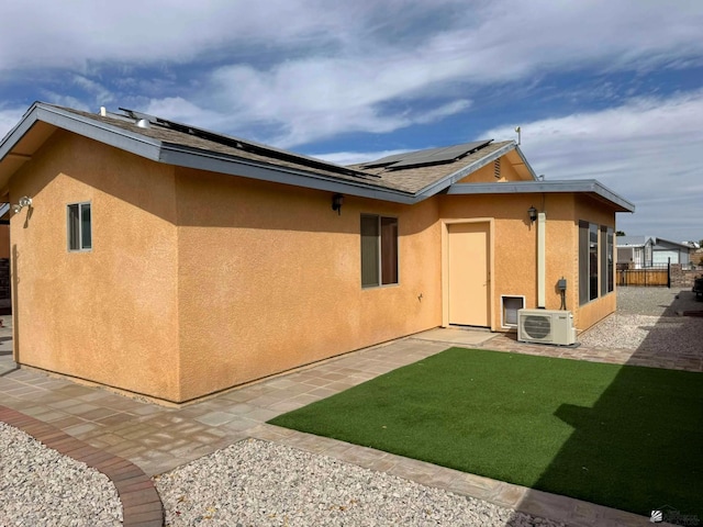 view of side of home featuring solar panels, ac unit, a patio area, and stucco siding