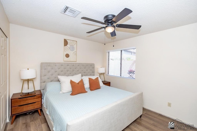 bedroom with wood finished floors, visible vents, and a textured ceiling