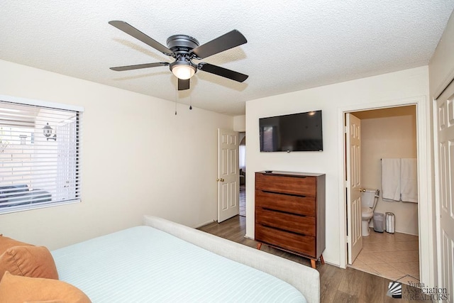 bedroom with dark wood finished floors, ensuite bath, ceiling fan, and a textured ceiling