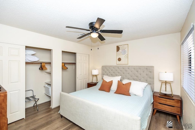 bedroom with a ceiling fan, wood finished floors, two closets, and a textured ceiling