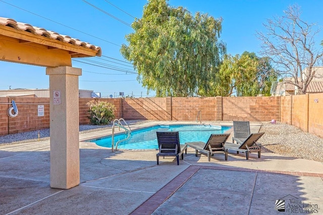 community pool with a patio area and a fenced backyard