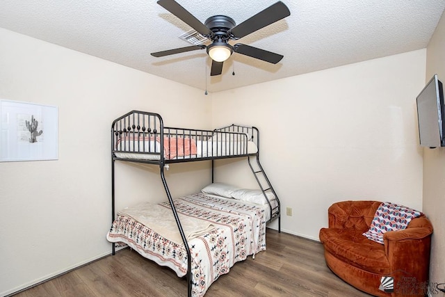 bedroom featuring ceiling fan, baseboards, a textured ceiling, and wood finished floors