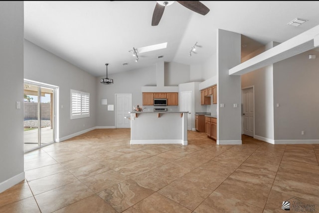 unfurnished living room featuring high vaulted ceiling, a skylight, rail lighting, light tile patterned floors, and ceiling fan