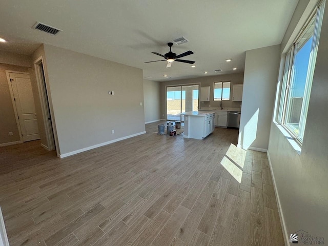 unfurnished living room featuring ceiling fan, light hardwood / wood-style floors, and sink