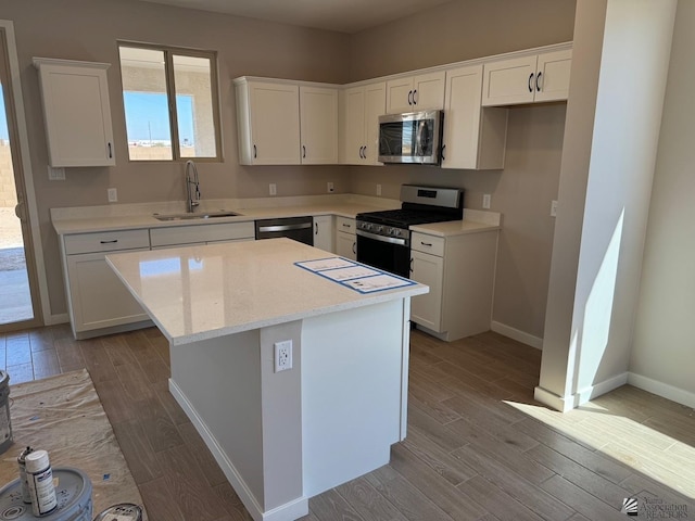 kitchen featuring sink, white cabinets, stainless steel appliances, and a kitchen island