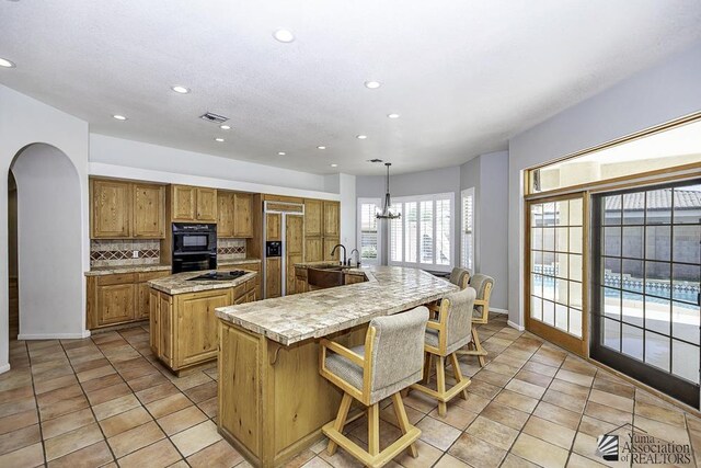 kitchen featuring a kitchen breakfast bar, hanging light fixtures, paneled refrigerator, tasteful backsplash, and a large island