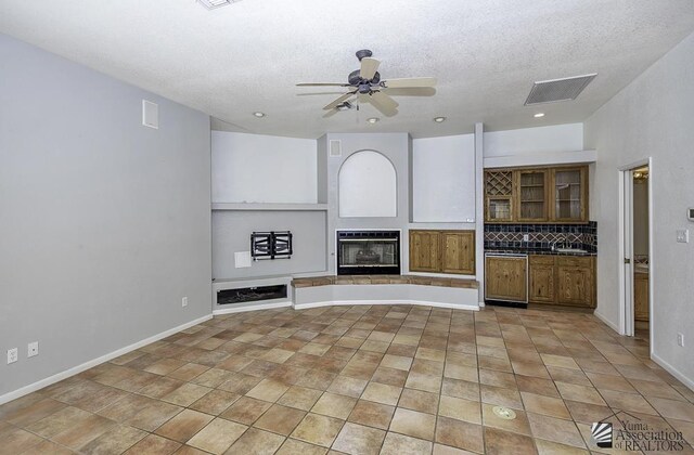 unfurnished living room with built in shelves, a textured ceiling, and ceiling fan