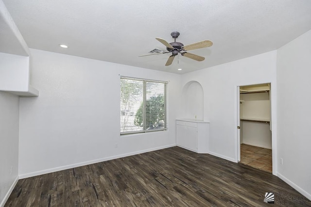 unfurnished bedroom featuring dark hardwood / wood-style flooring, ceiling fan, a closet, and a spacious closet