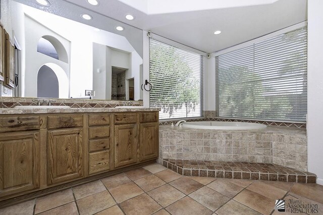 bathroom featuring tiled tub, tile patterned flooring, and vanity