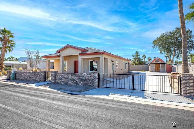 view of front of home featuring a fenced front yard, a gate, a tiled roof, and stucco siding