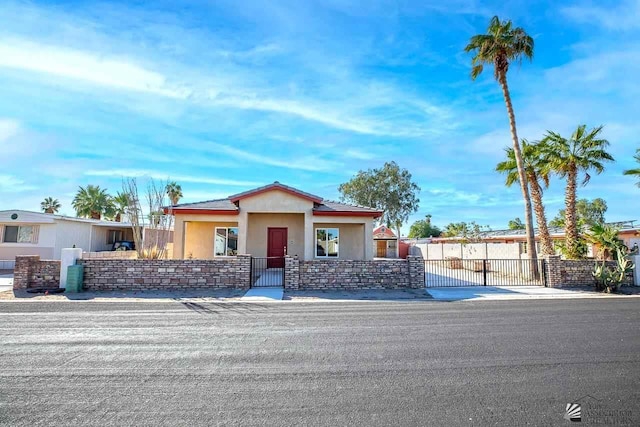 view of front facade with a fenced front yard, a gate, and stucco siding