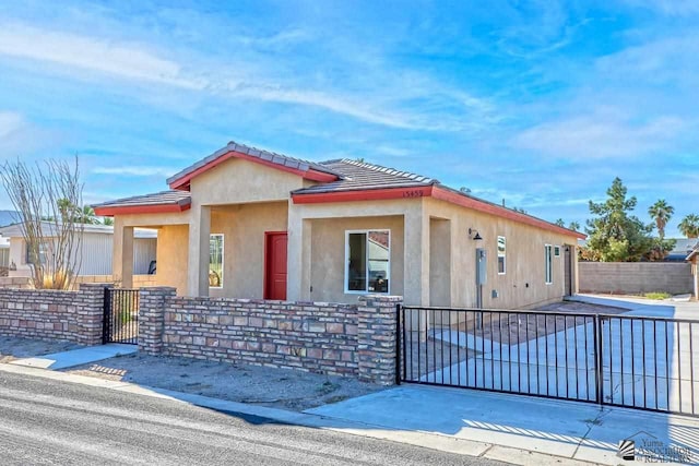 view of front of property featuring a gate, fence, a tiled roof, and stucco siding