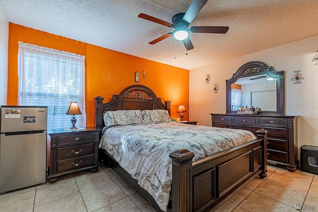 bedroom featuring a ceiling fan, freestanding refrigerator, a textured ceiling, and light tile patterned floors