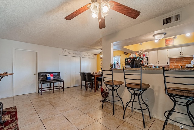 kitchen featuring visible vents, white cabinets, dark countertops, a breakfast bar, and freestanding refrigerator