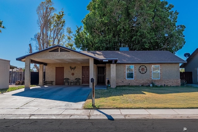 ranch-style house featuring driveway, fence, a front yard, a carport, and stucco siding