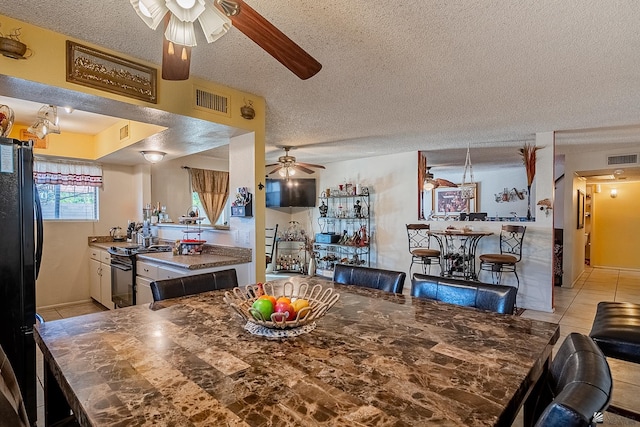 dining room featuring a textured ceiling, visible vents, and a ceiling fan