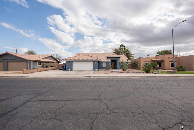 view of front of home with fence, an attached garage, stucco siding, concrete driveway, and a tile roof