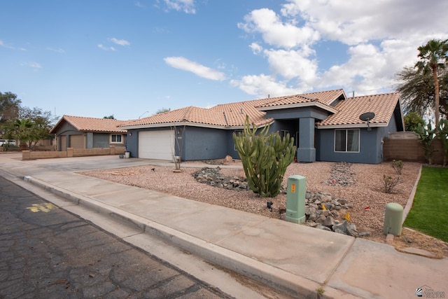 view of front of property with stucco siding, driveway, fence, an attached garage, and a tiled roof