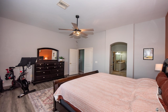 bedroom featuring ceiling fan, visible vents, arched walkways, and wood finished floors