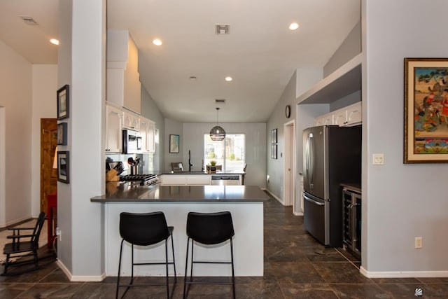 kitchen featuring visible vents, a peninsula, stainless steel appliances, white cabinets, and dark countertops