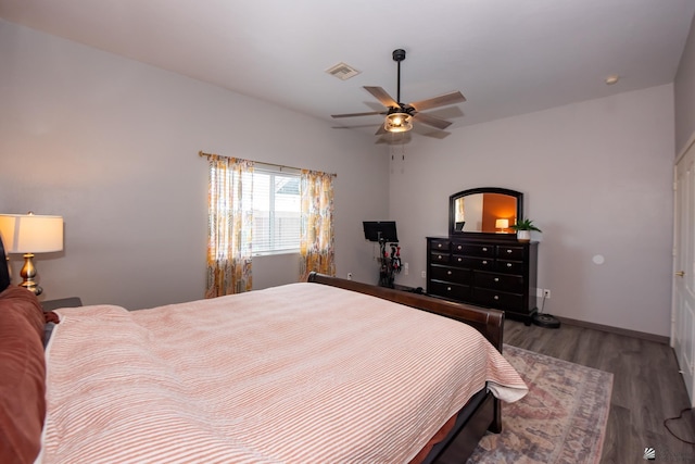 bedroom featuring visible vents, a ceiling fan, baseboards, and wood finished floors