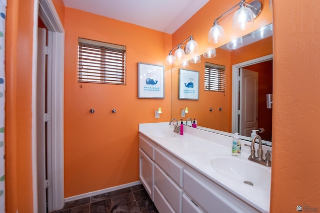 bathroom with double vanity, tile patterned flooring, baseboards, and a sink