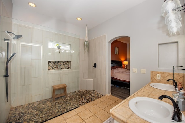 ensuite bathroom with tile patterned floors, ensuite bathroom, walk in shower, and a sink