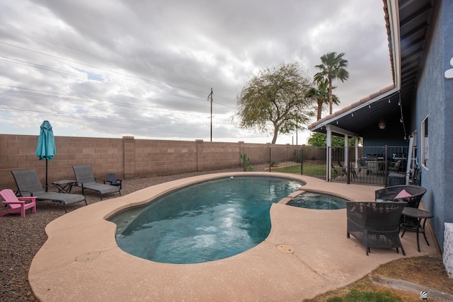 view of swimming pool featuring a patio, a fenced backyard, and a pool with connected hot tub