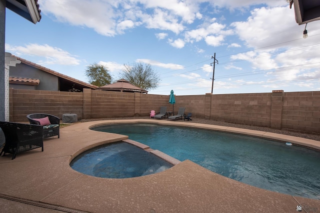 view of swimming pool featuring a patio, a fenced backyard, and a pool with connected hot tub