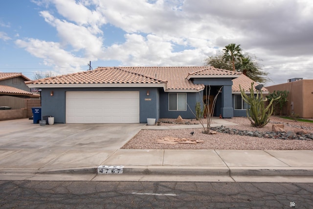 view of front of house featuring concrete driveway, a tiled roof, an attached garage, and stucco siding