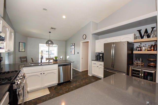 kitchen with a peninsula, a sink, stainless steel appliances, vaulted ceiling, and white cabinetry