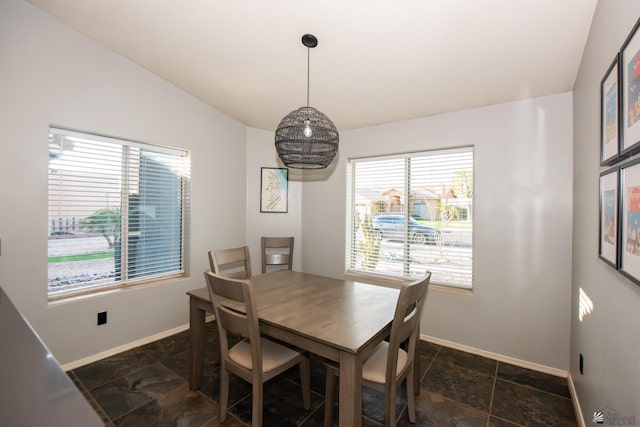 dining area featuring stone finish floor, baseboards, and lofted ceiling