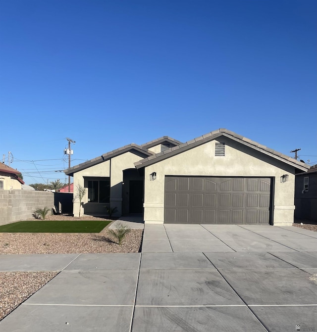 view of front facade with an attached garage, fence, a tile roof, driveway, and stucco siding