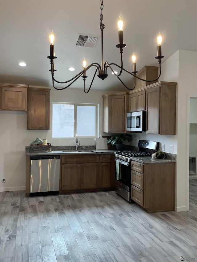 kitchen with light wood finished floors, appliances with stainless steel finishes, a sink, and visible vents