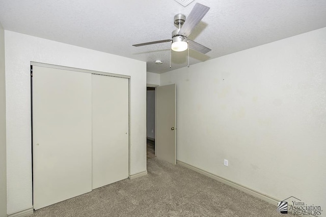 unfurnished bedroom featuring light carpet, a closet, a textured ceiling, and a ceiling fan