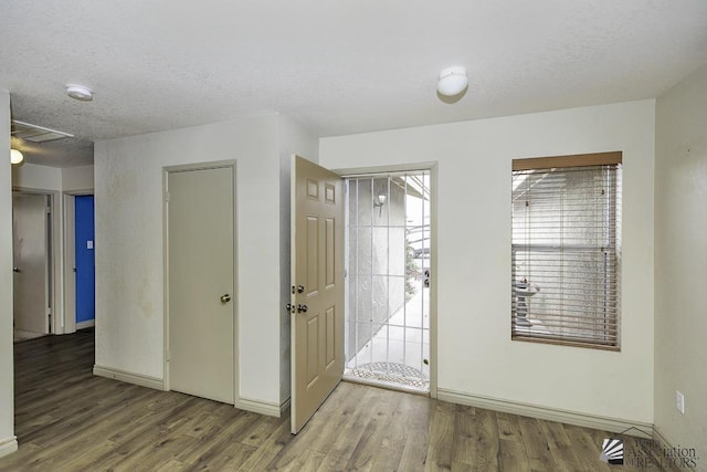 foyer entrance featuring a textured ceiling, baseboards, and wood finished floors