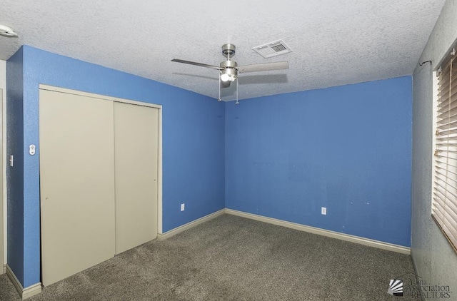 unfurnished bedroom featuring a textured ceiling, carpet flooring, visible vents, a ceiling fan, and a closet