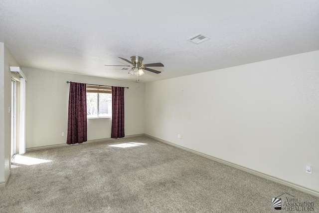 carpeted empty room with a ceiling fan, visible vents, a textured ceiling, and baseboards