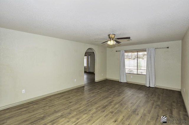 spare room featuring baseboards, arched walkways, ceiling fan, wood finished floors, and a textured ceiling